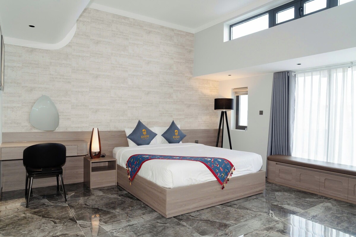 A modern hotel room with a large bed, a desk, and a chair.