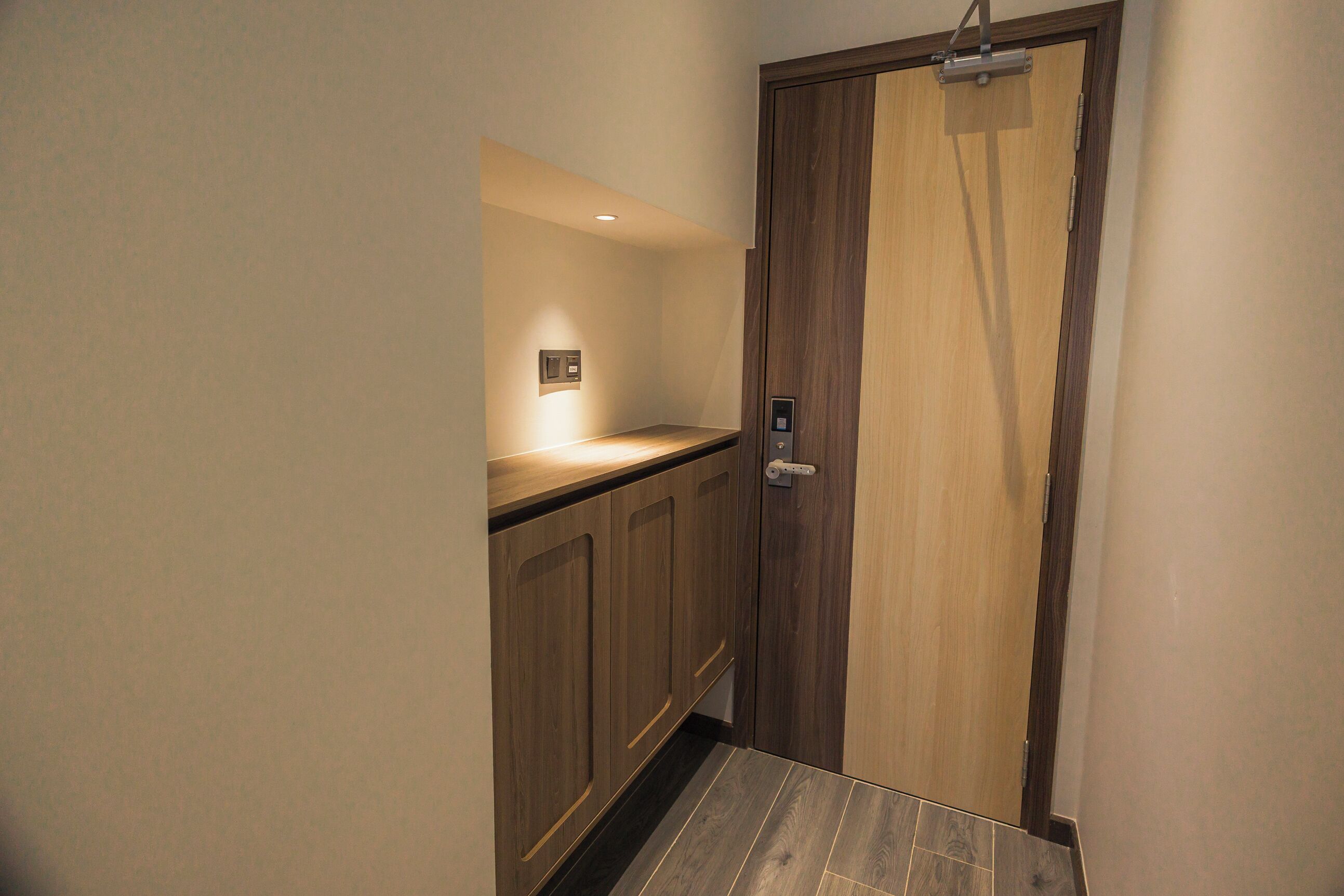 A narrow hallway with wooden cabinets and a door with a handle.
