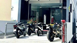 En modern byggnad med skylten ”NJUT AV DIN LÄGENHET” och ett antal motorcyklar parkerade framför.