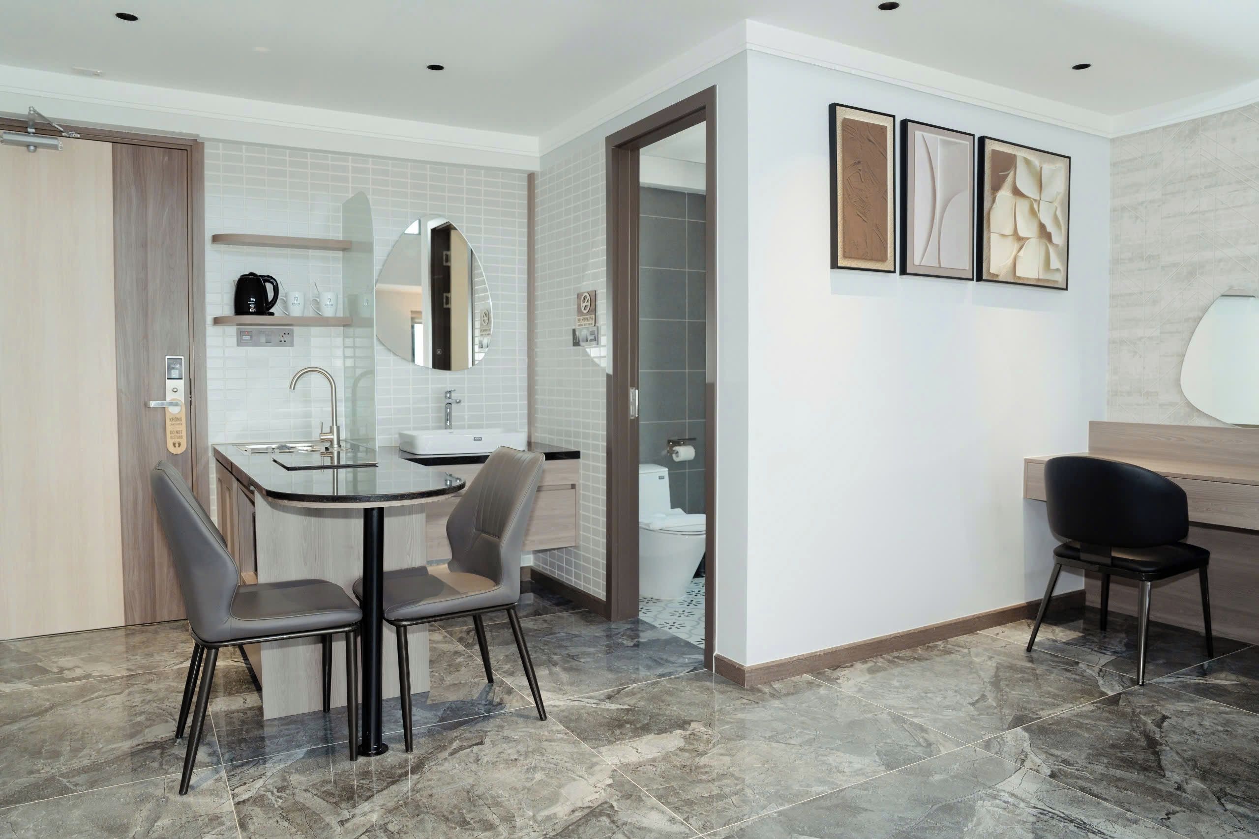 A modern hotel room with a dining area, a bathroom, and a seating area.