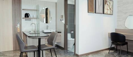 A modern hotel room with a dining area, a bathroom, and a seating area.