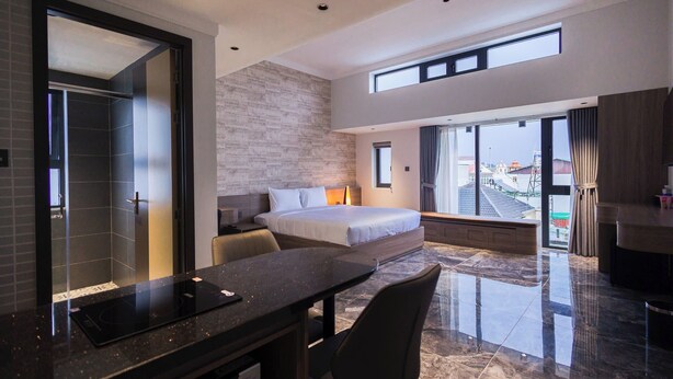 Ett modernt hotellrum med en stor säng, ett skrivbord och utsikt över staden.