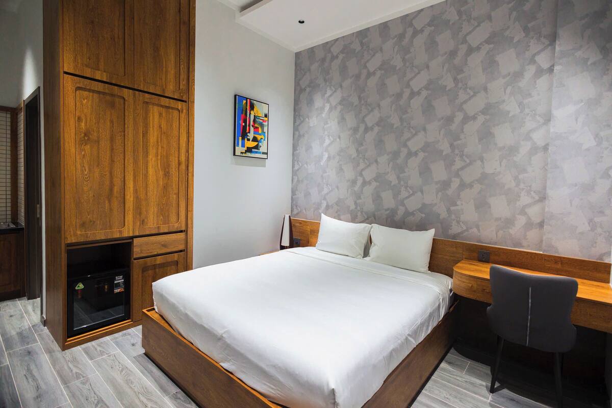 Un dormitorio con cama, armario de madera y escritorio con silla.