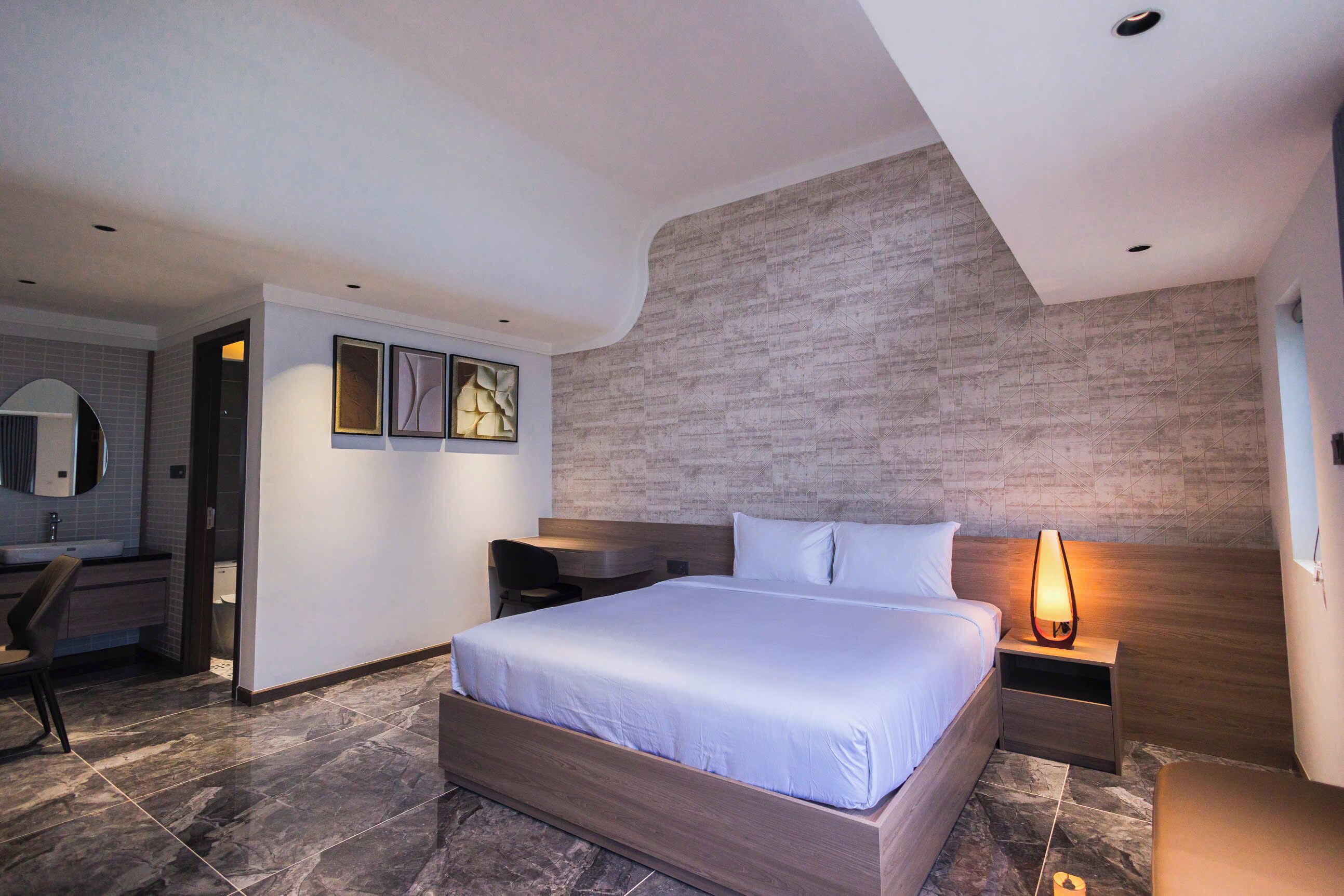 Ein modernes Hotelzimmer mit einem großen Bett, einem Schreibtisch, einem Stuhl und einem Badezimmer.