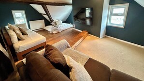 Ruime loft slaapkamer met een groot bed, een bank en een televisie aan de muur.