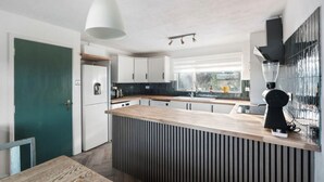 Een moderne keuken met witte kasten, een houten eiland, een koffieapparaat en uitzicht op het buitengebied.