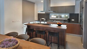 A modern kitchen with a central island, bar stools, and a dining table with chairs.