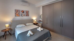 A modern hotel room with a large bed, two bedside tables with lamps, a wardrobe, and artwork on the wall.