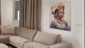 A living room with a beige sofa, a round coffee table, and a painting on the wall.