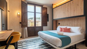 A hotel room with a bed, a desk with a chair, a window, and a view of the outside. - The Central House Granada Elvira Hostel (Granada)