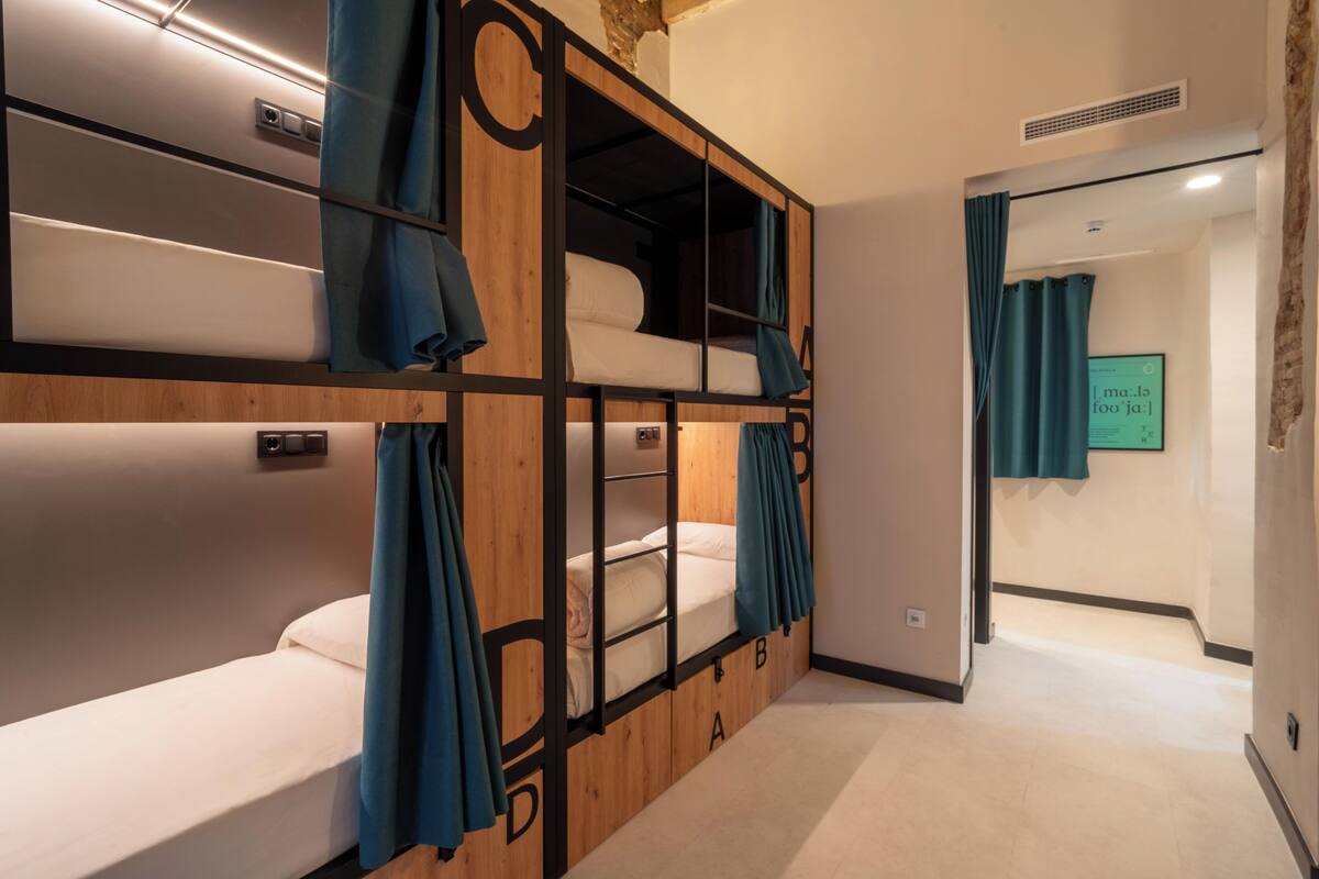 A bunk bed room with a wooden design, a flat-screen TV, and a visible door leading to another room.