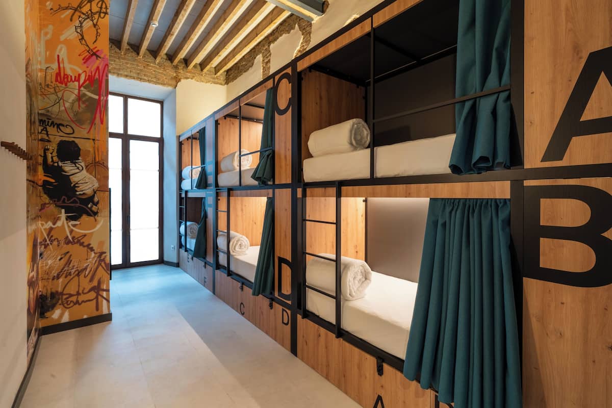 Une chambre de dortoir avec des lits superposés, des murs en bois et un mur couvert de graffitis.