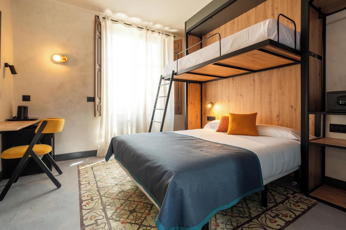 Une chambre avec un lit superposé, un bureau, une chaise et un tapis à motifs.