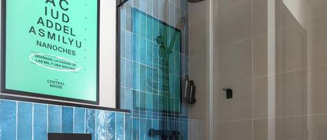 A modern bathroom with a glass shower enclosure, a white toilet, and blue-tiled walls.