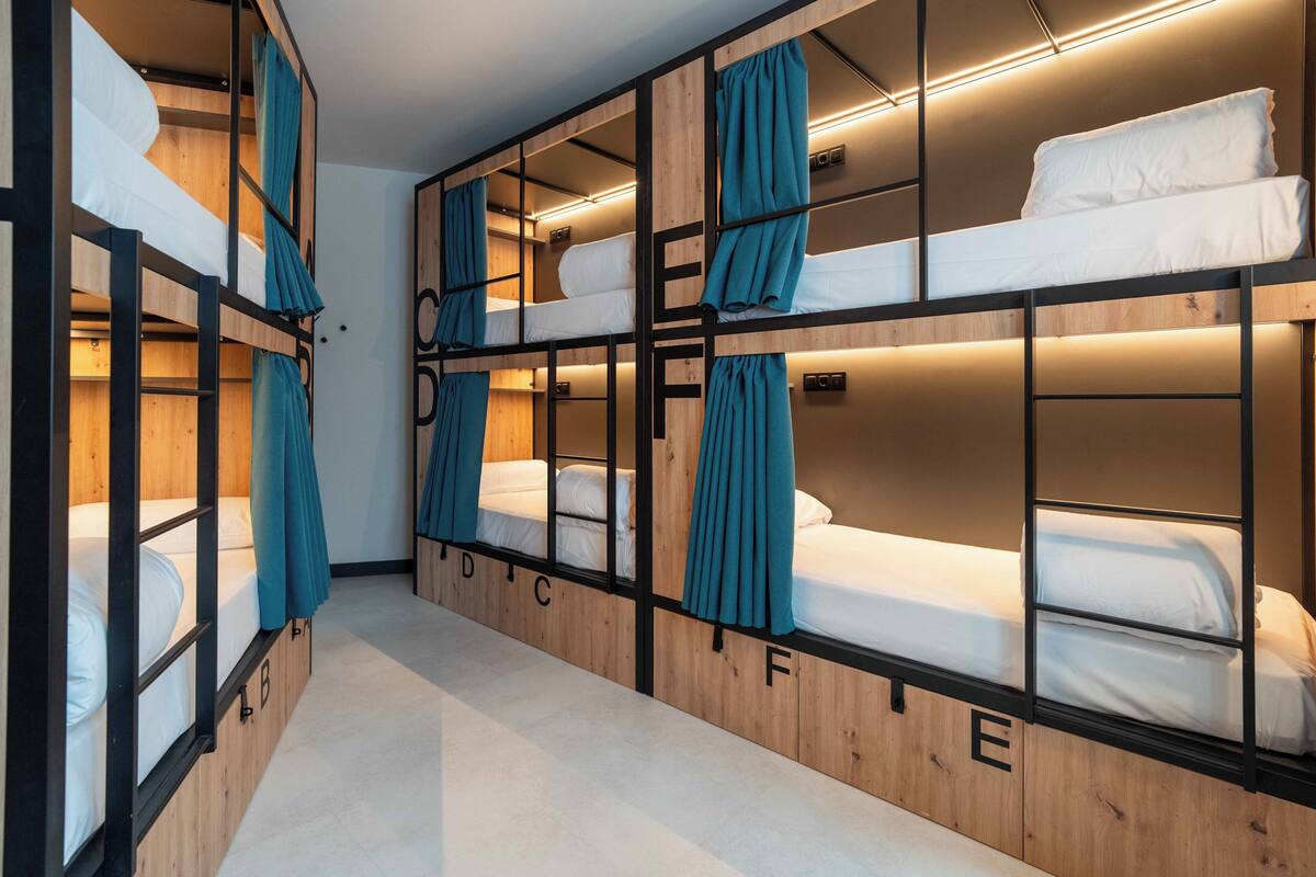 Une chambre de type dortoir, avec des lits superposés, des murs en bois et des rideaux.