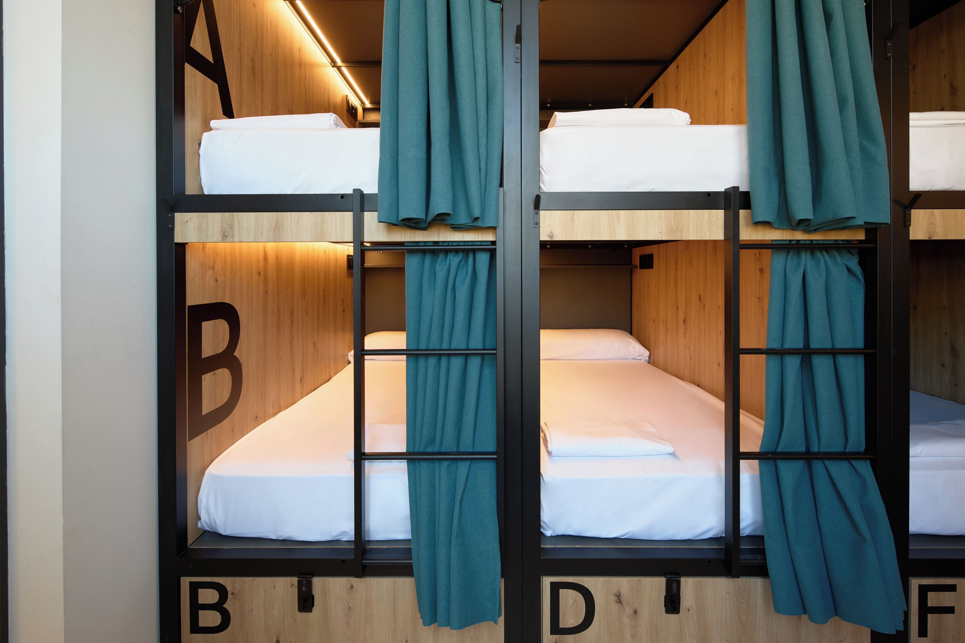 A bunk bed room with wooden walls and teal curtains.
