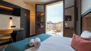 Een hotelkamer met een bed, een bureau, een stoel en een balkon met stoelen.