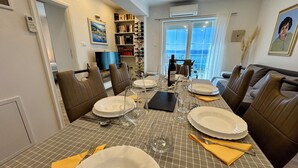 A dining area with a checkered tablecloth, brown leather chairs, and a view of the sea through large windows. - Apartment Toma 1 (Crikvenica)