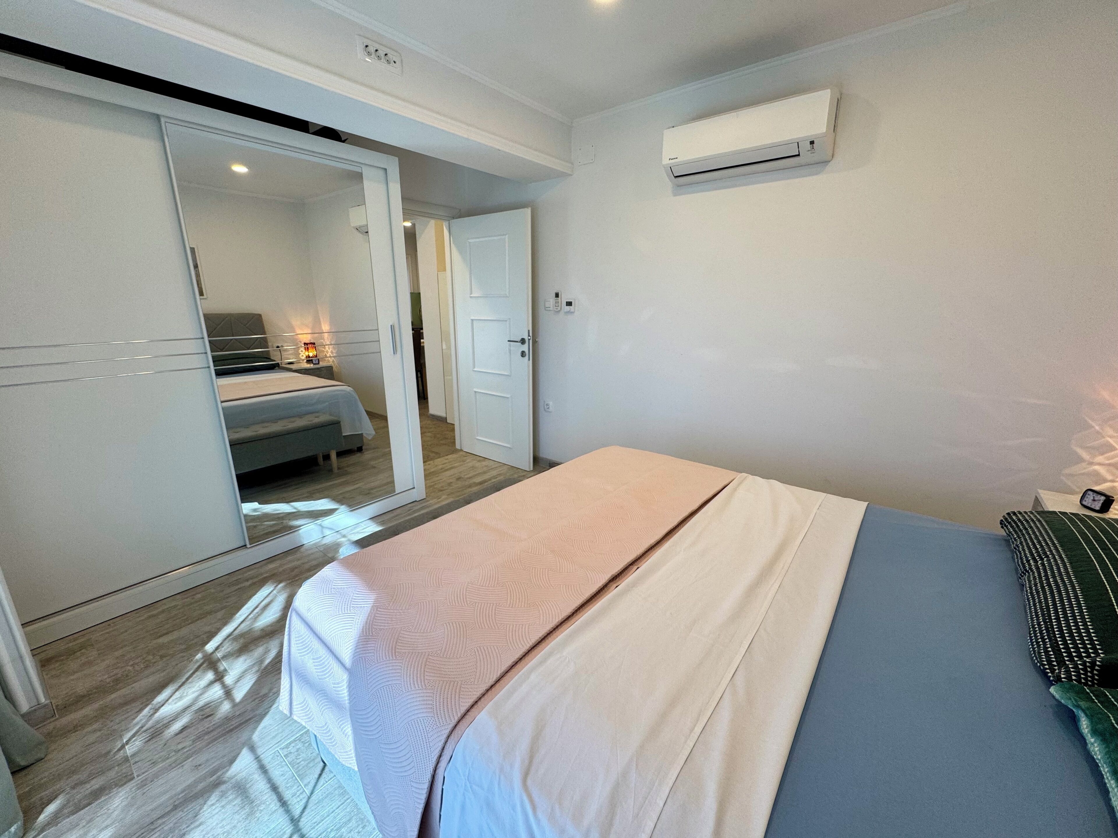Een slaapkamer met een bed, een kledingkast, een nachtkastje en een airconditioning.