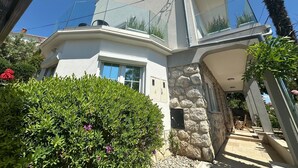 A modern house with a stone facade, large windows, and a balcony with plants. - Apartment Toma 1 (Crikvenica)