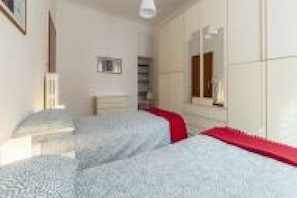 Een slaapkamer met twee bedden, een kaptafel, een spiegel en een raam.