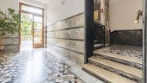 Ein Flur mit Fliesenboden, einer Treppe und einer Tür zum Außenbereich.