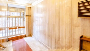 A hotel corridor with wooden panel walls, a bench, and a window with a view. - GuestHost - Porto Antico Apartment (Genova)