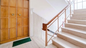 A staircase with wooden handrails and a wooden door with multiple panels. - GuestHost - Porto Antico Apartment (Genova)