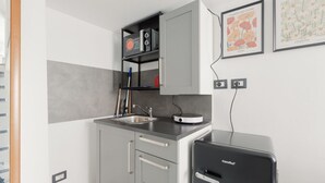 Eine kompakte Küche mit einem Einbaukühlschrank, einem Spülbecken und einer Kaffeemaschine.