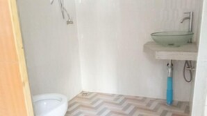Un baño pequeño con inodoro, lavamanos de vidrio y ducha.