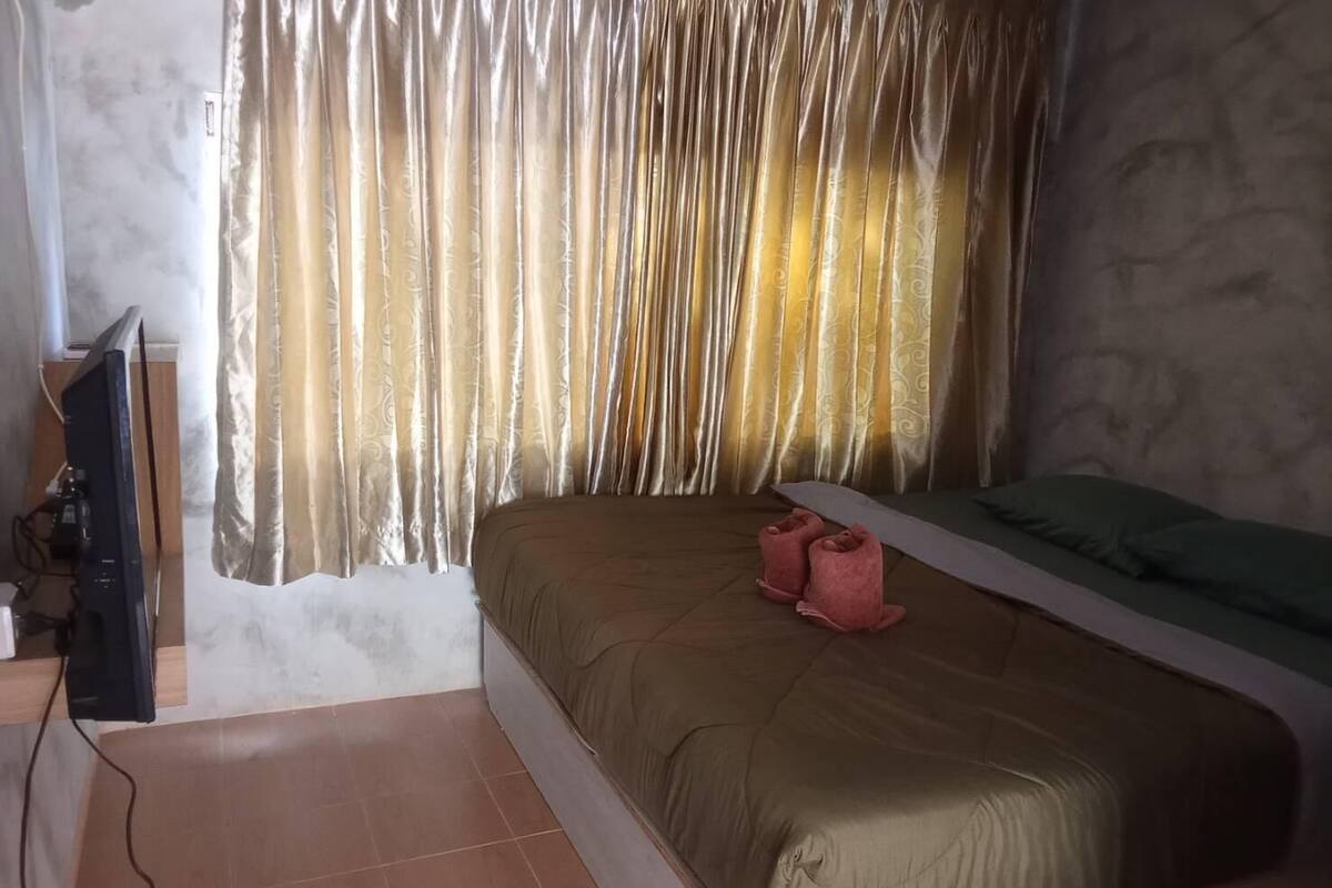 Un dormitorio con cama, televisor y cortina.