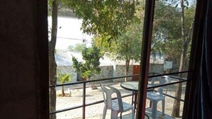A balcony with a table and chairs, a view of trees and a building in the background. - The Resort Lamtakong (Pak Chong)