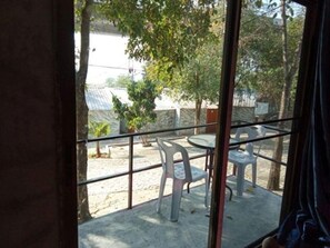 A balcony with a table and chairs, a view of trees and a building in the background. - The Resort Lamtakong (Pak Chong)
