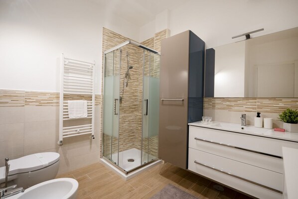 Une salle de bain moderne avec une douche à parois de verre, un lavabo blanc et un grand miroir.