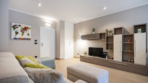 Un salon moderne comprenant un canapé, un pouf, un téléviseur et des étagères intégrées.