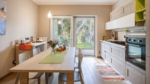 Une cuisine moderne avec un coin repas, de grandes fenêtres et une vue sur les arbres.