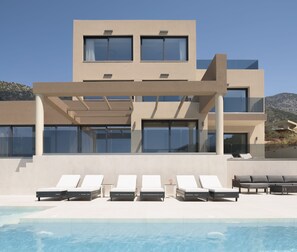 A modern two-story building with a pool area in front. - Luxurious Villa Dias With Tennis Court by Estia (Mylopotamos)