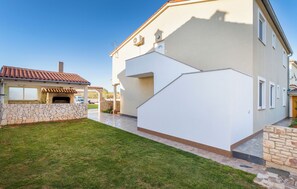 Una casa moderna con un caminetto in pietra, un muro in pietra e un prato curato.