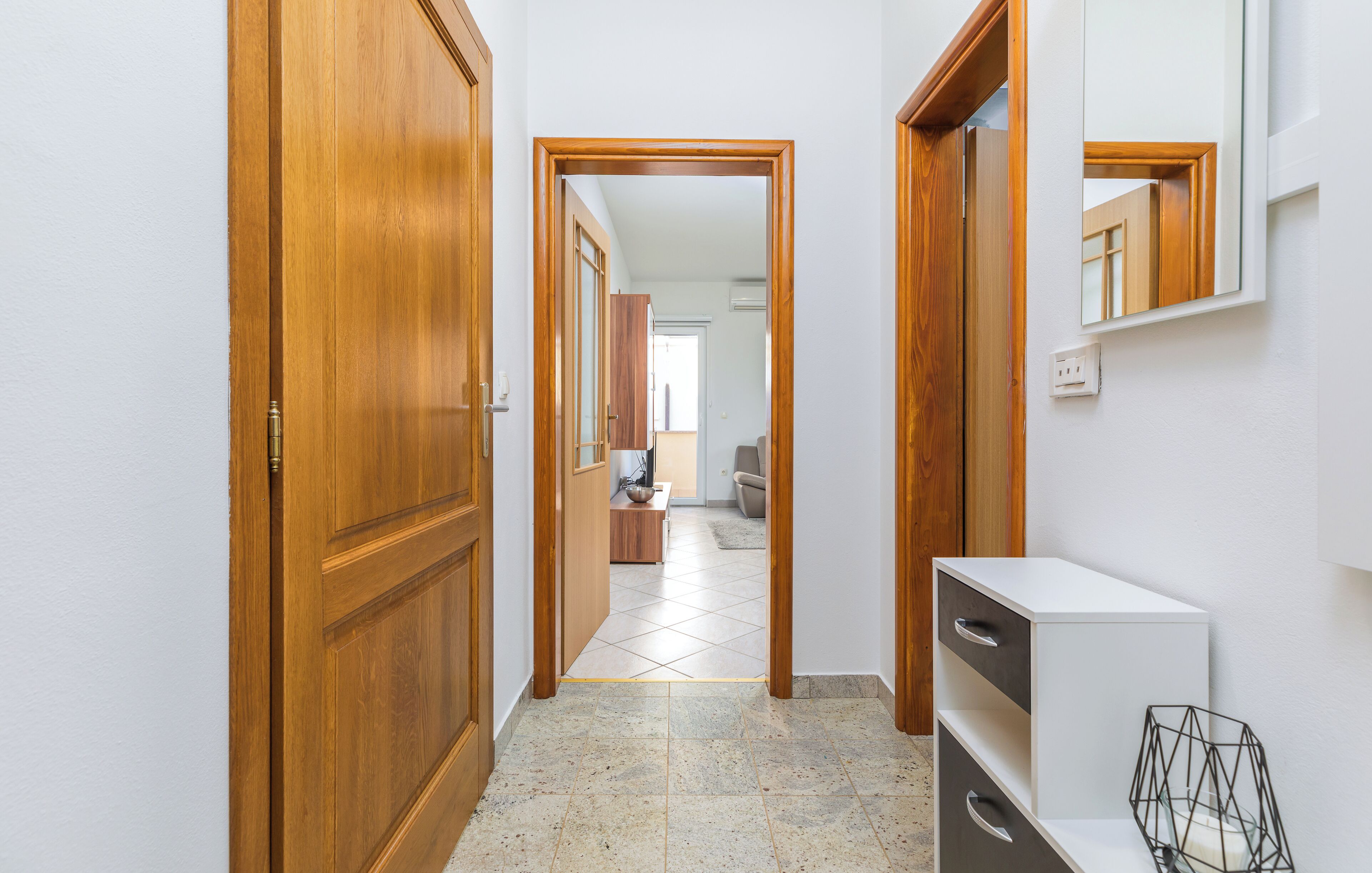 A hallway with wooden doors, a white console table, and a tiled floor.