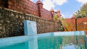 Ein rechteckiger Swimmingpool mit klarem, blauen Wasser, umgeben von Stein- und Backsteinmauern.