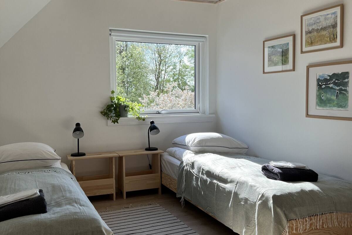 A bedroom with two beds, a window, a desk, and a ceiling light.