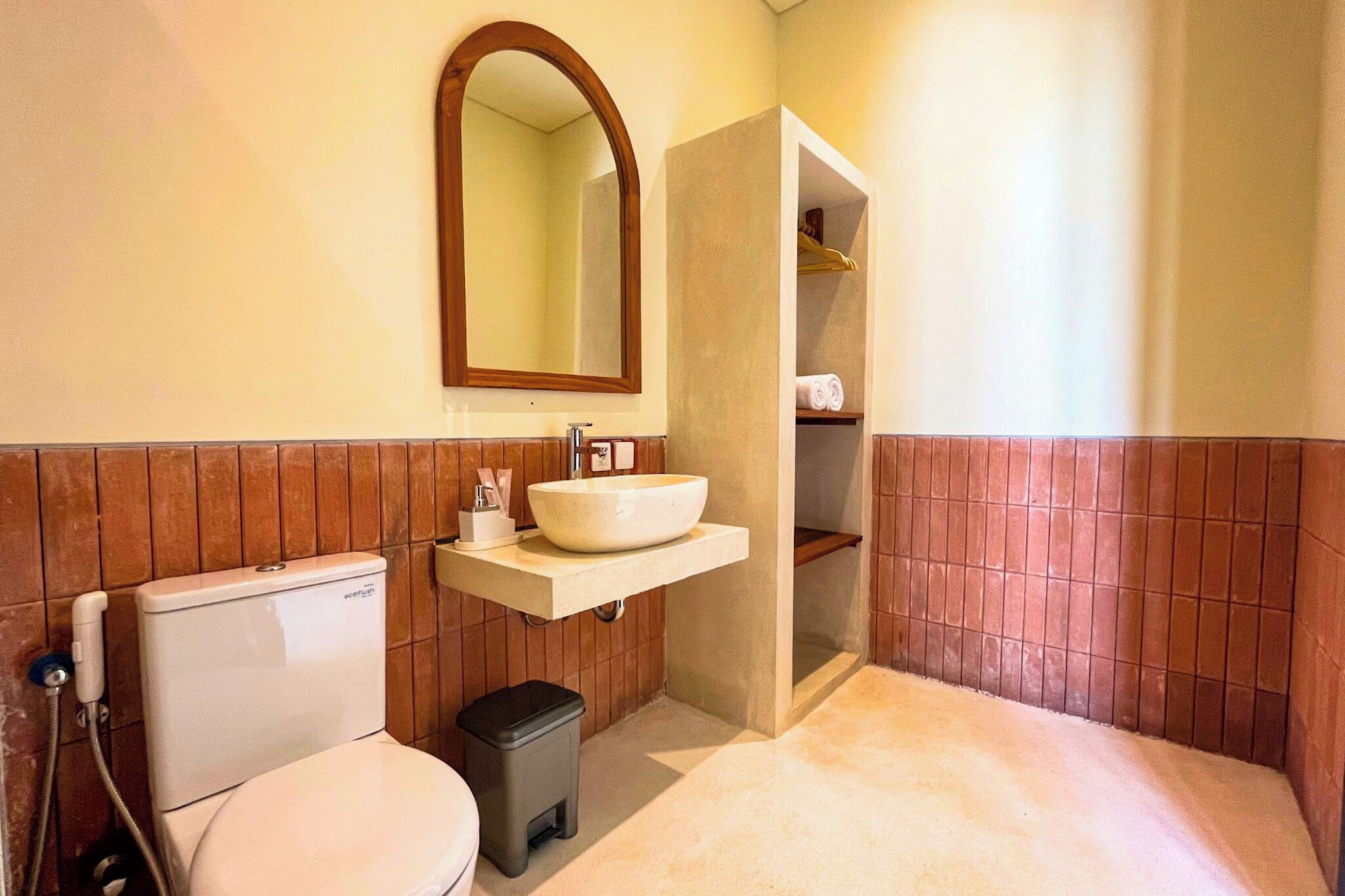Une salle de bain avec des toilettes blanches, un lavabo blanc avec un miroir au-dessus, et un espace douche.
