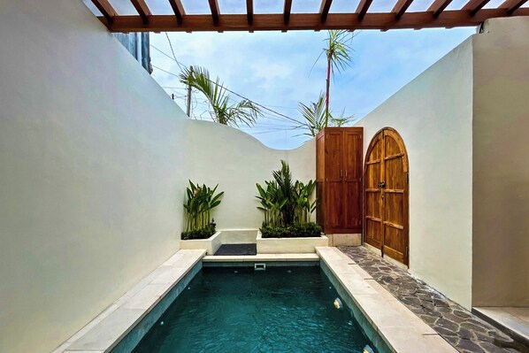 A pool area with a pergola, wooden door, and potted plants. - Esha Private Pool Villas by AGATA (Ungasan)