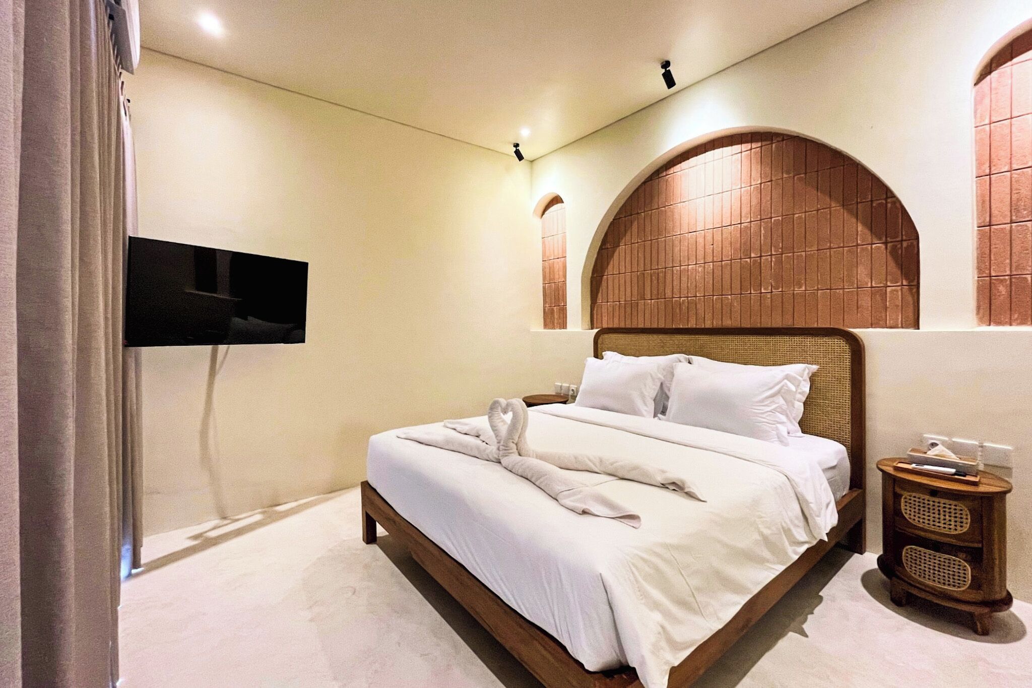 Ein Hotelzimmer mit einem großen Bett, einem flachbildfernseher an der Wand und einem hölzernen Kopfteil.