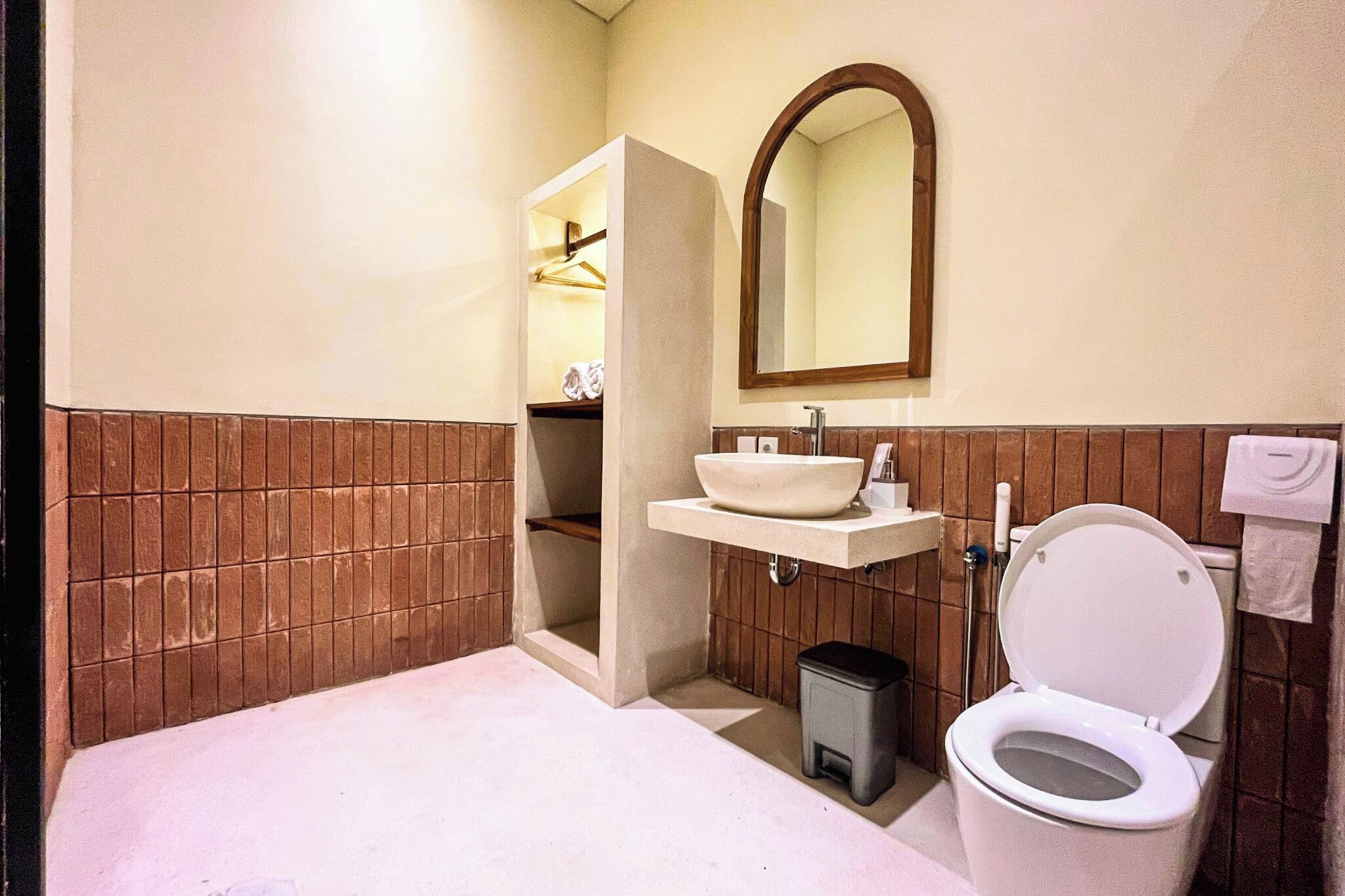 A bathroom with a white sink, a toilet, a mirror, and a towel rack.
