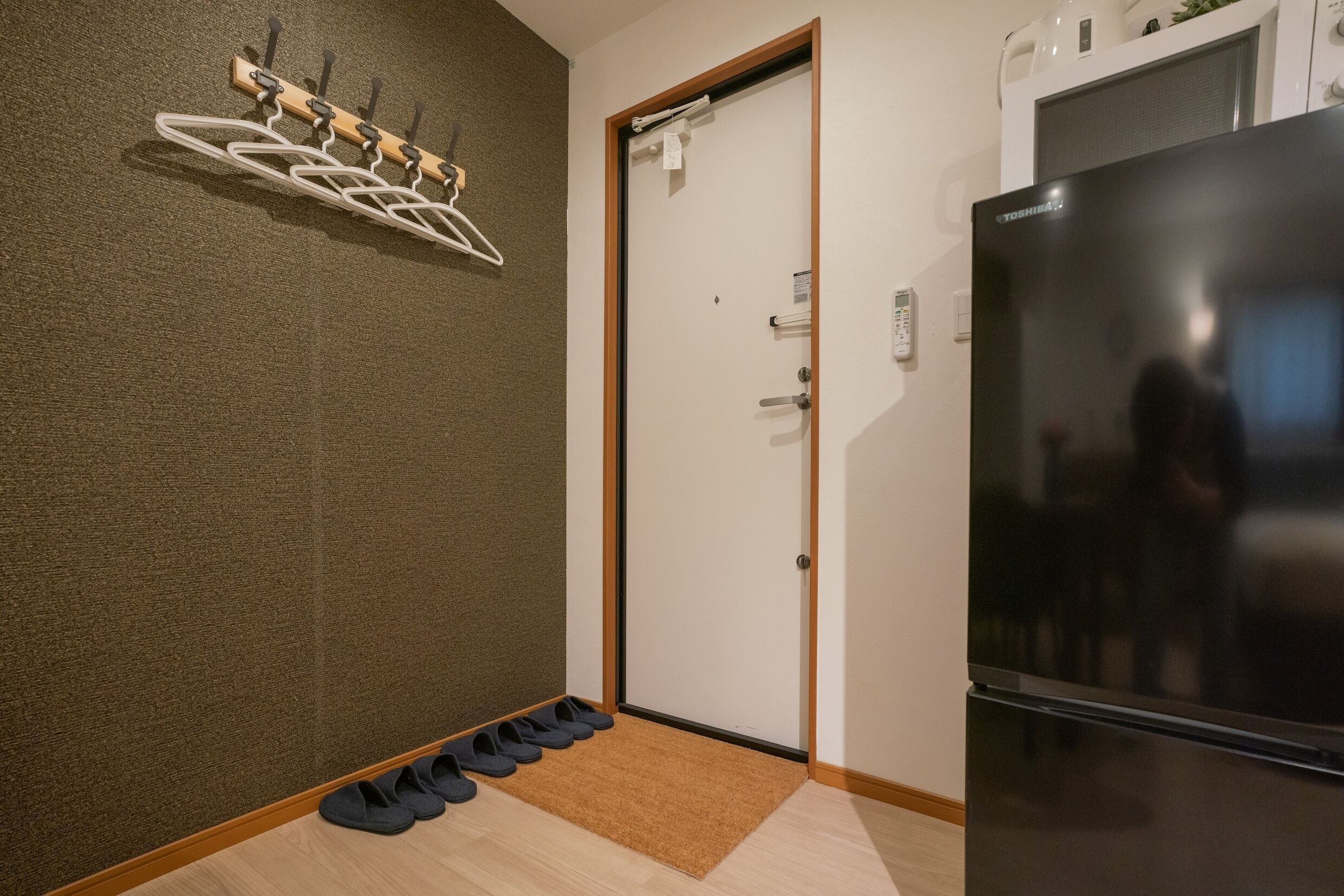 Ein Flur mit Kleiderhaken, einer Tür und einem Kühlschrank.