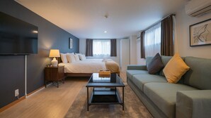 Une chambre d’hôtel moderne équipée d’un lit, d’un canapé, d’une télévision et d’un bureau.