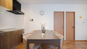 Une cuisine moderne avec des meubles en bois, une hotte en acier inoxydable et un coin repas comprenant une table en bois et six chaises.