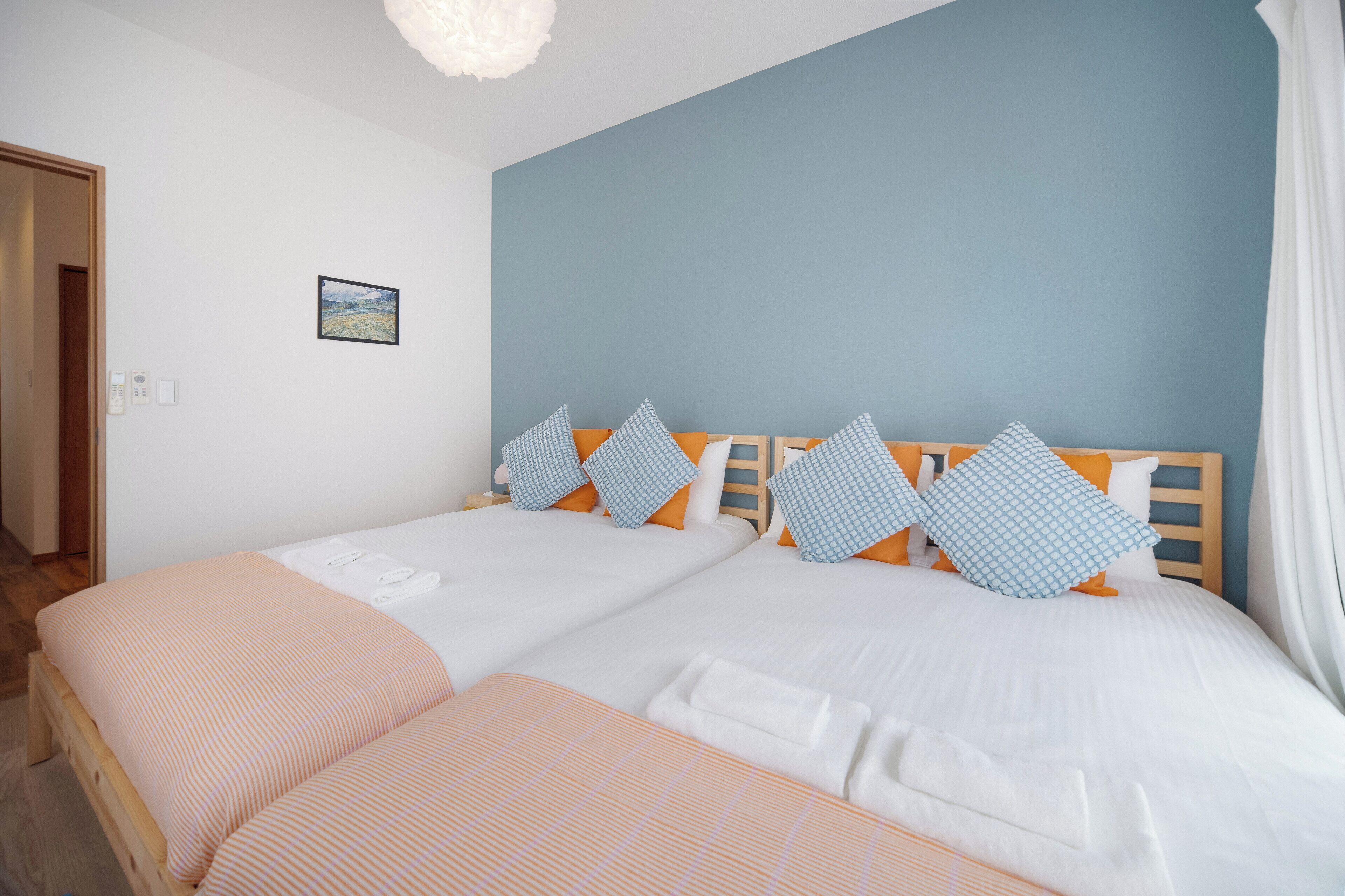 A double bed with a wooden headboard, two pillows, and a white blanket.