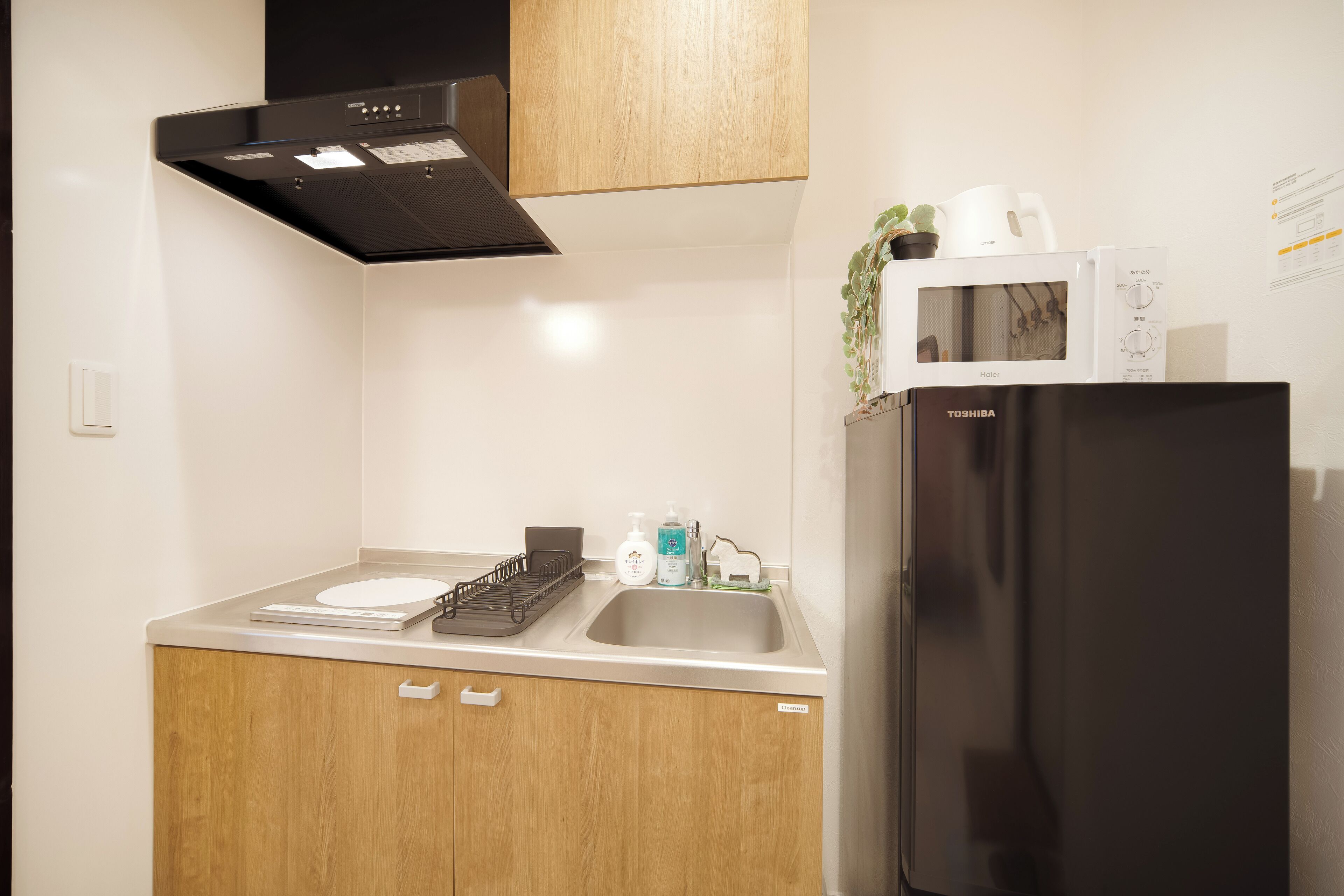 A compact kitchen with a black refrigerator, a microwave, and a sink.